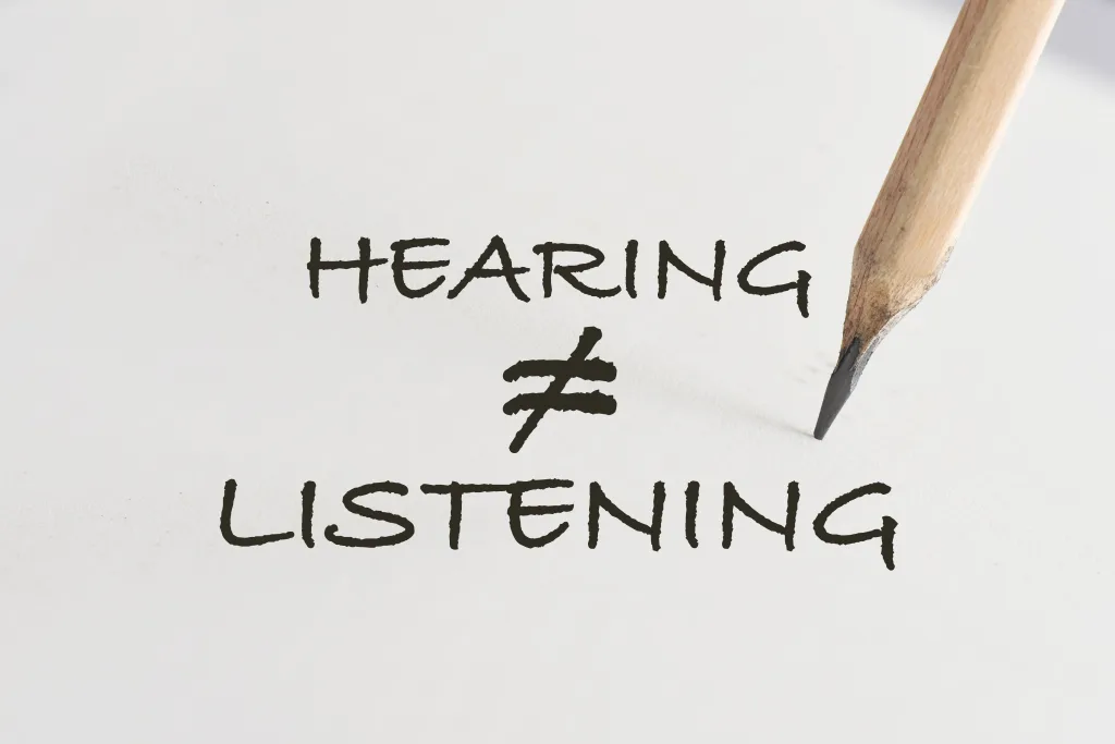 Hearing not equal listening written on white paper with pencil. Communication with understanding concept and soft skill idea